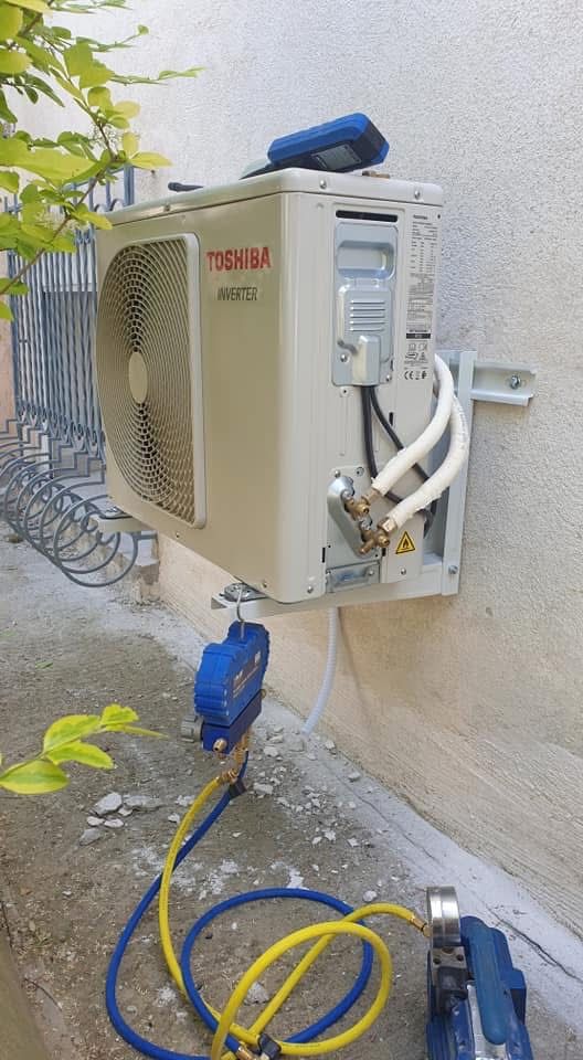 Unité extérieure de climatisation Toshiba fixée au mur, manomètres et flexibles branchés pour la mise en service